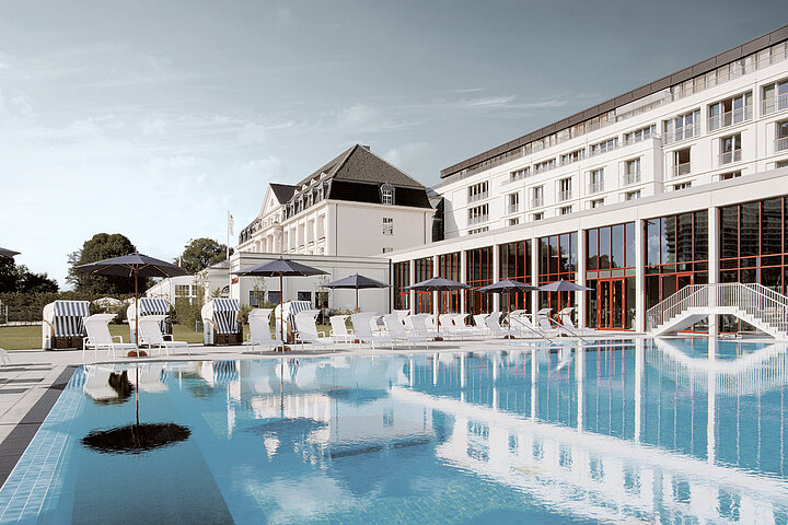 Outdoorpool am Hotel mit weißer Fassade, bewölkter Himmel