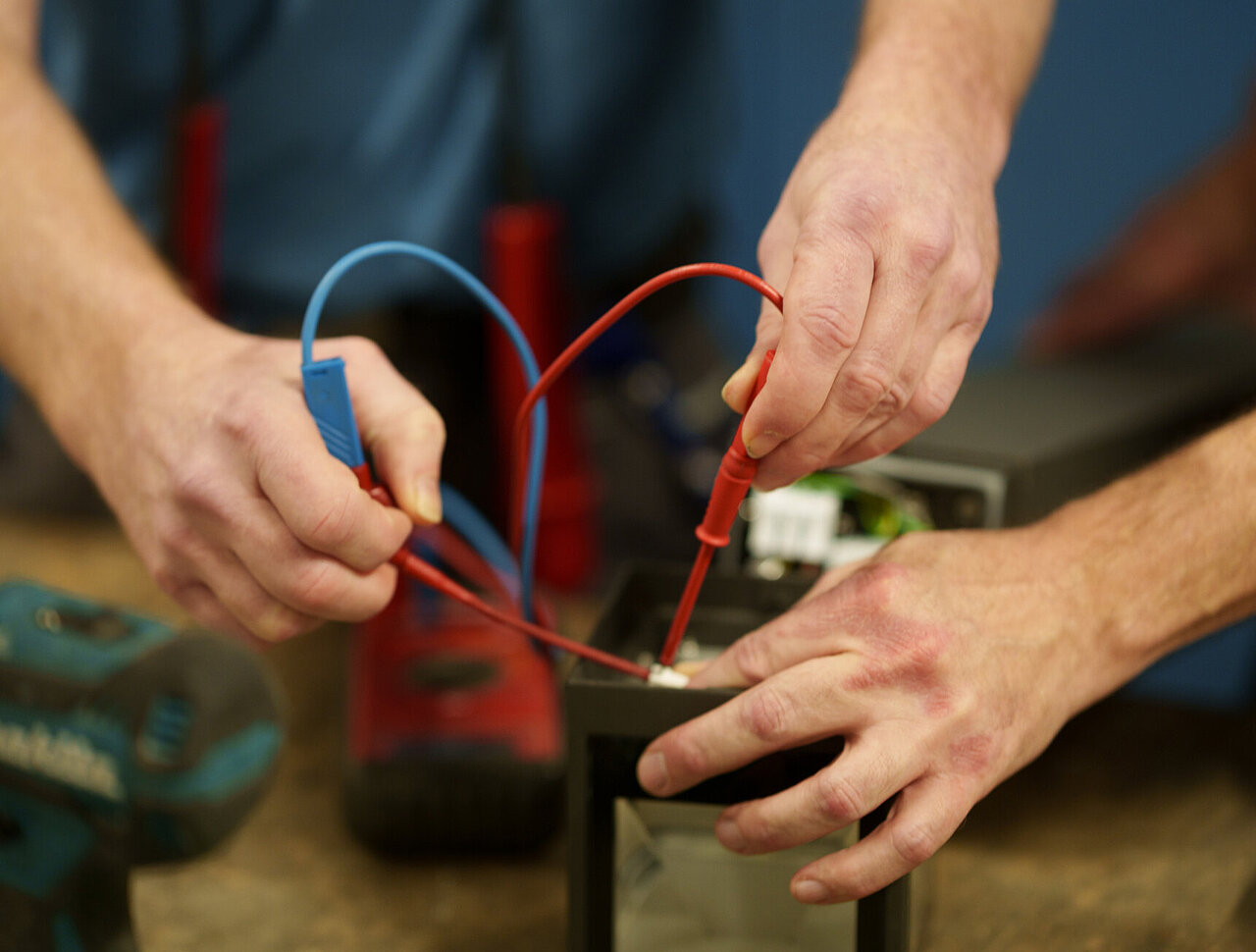 DSR_Asset_Werte Handwerker prüft mit Multimeter eine elektrische Verbindung