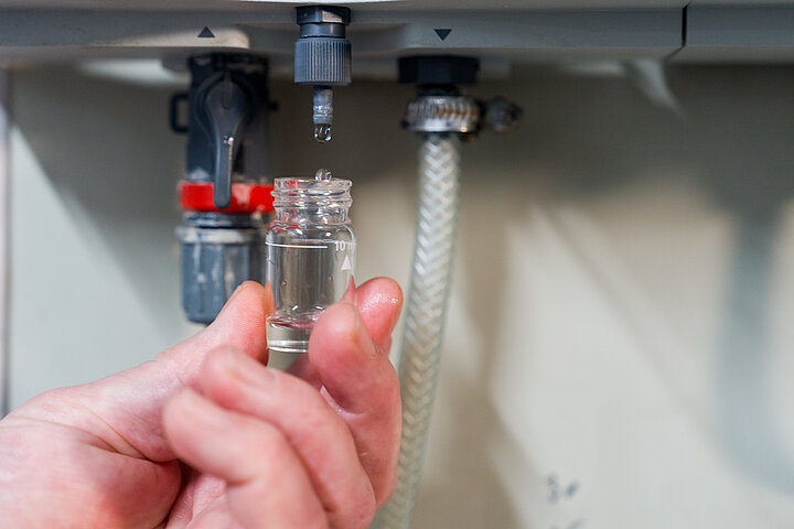 Technische Facility Services von DSR Asset Management Fläschchen, das sich mit Wassertropfen füllt, gehalten von einer Hand
