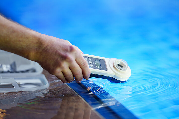 Technische Facility Services von DSR Asset Management Messgerät in einer Hand, das in ein Pool getaucht wird