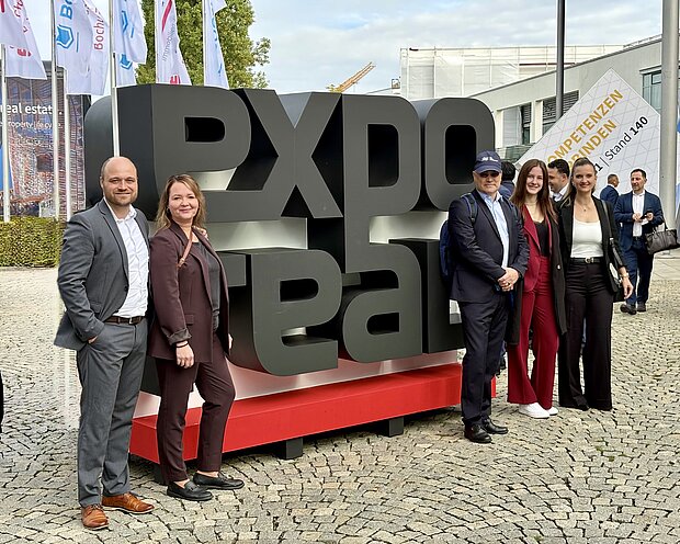 Fünf Personen stehen an den menschengroßen Buchstaben EXPO REAL