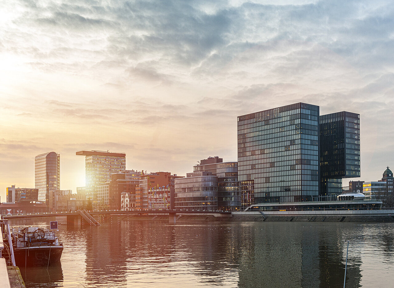 DSR_Asset_Standorte Skyline mit modernen Bürogebäuden am Wasser bei Sonnenuntergang, Medienhafen